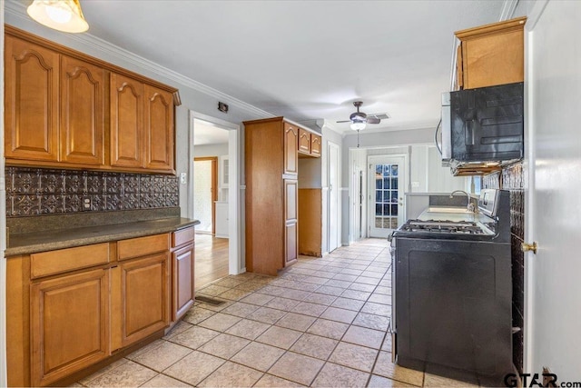 kitchen with decorative backsplash, ornamental molding, gas stove, and ceiling fan