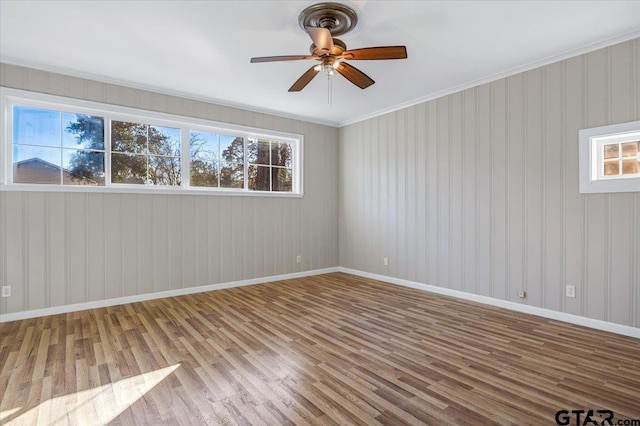 unfurnished room featuring ceiling fan, a healthy amount of sunlight, hardwood / wood-style floors, and ornamental molding