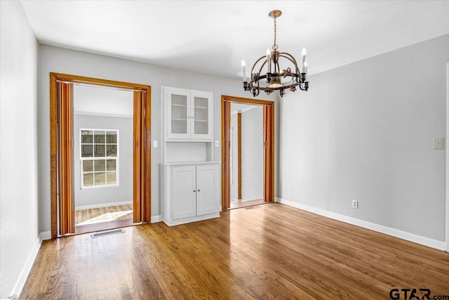 unfurnished dining area featuring hardwood / wood-style floors and a chandelier