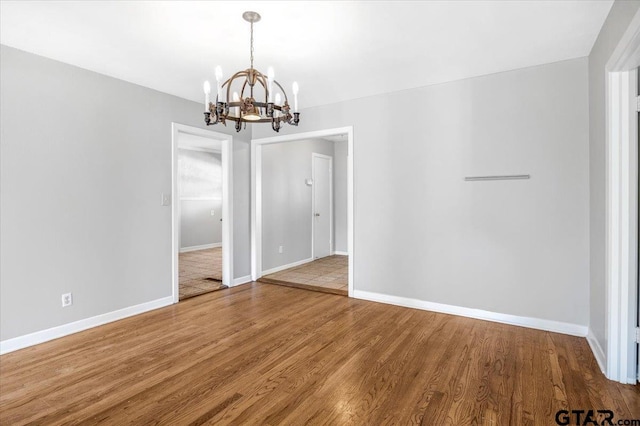 unfurnished dining area with an inviting chandelier and hardwood / wood-style flooring