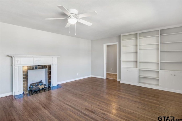 unfurnished living room with a tile fireplace, dark wood-type flooring, and ceiling fan