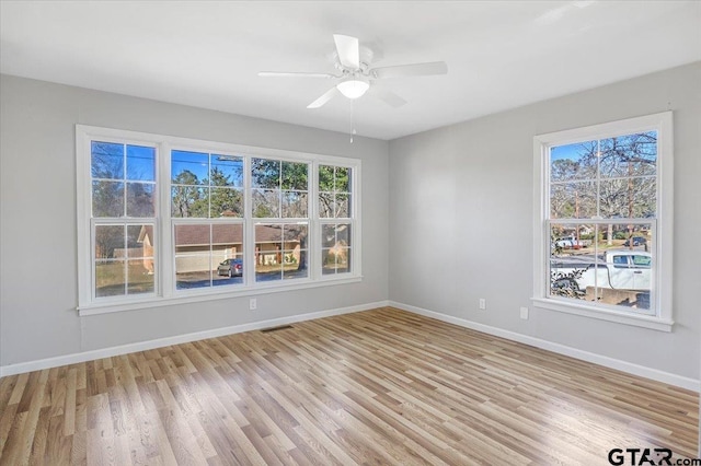 empty room with ceiling fan and light hardwood / wood-style flooring