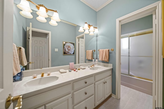 bathroom featuring shower / bath combination with glass door, crown molding, a sink, and double vanity