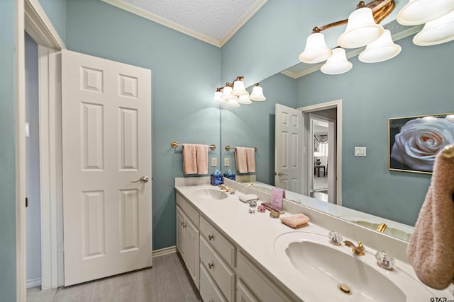 full bathroom featuring double vanity, a textured ceiling, ornamental molding, and a sink