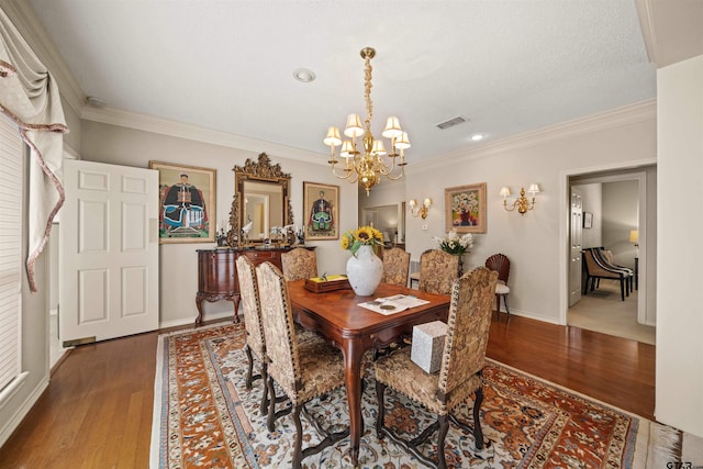dining area featuring wood finished floors, visible vents, crown molding, baseboards, and a chandelier