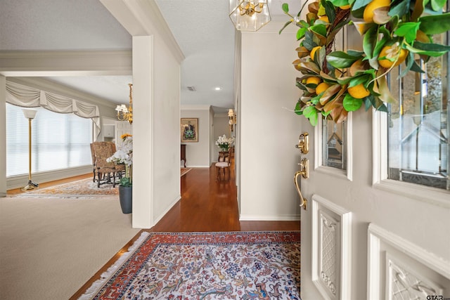 foyer with baseboards, a notable chandelier, wood finished floors, and crown molding