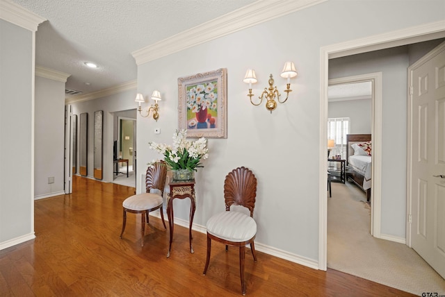 sitting room with wood finished floors, crown molding, and baseboards