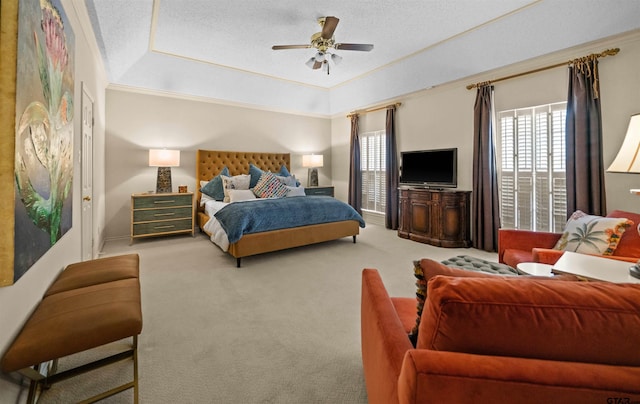 carpeted bedroom with a ceiling fan, multiple windows, crown molding, and a tray ceiling