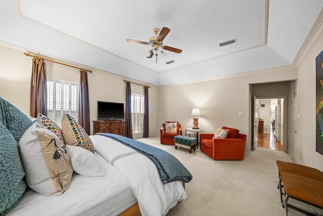 carpeted bedroom featuring a tray ceiling, ceiling fan, visible vents, and multiple windows