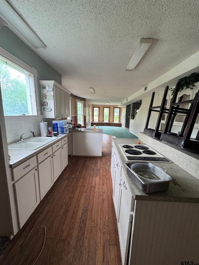 kitchen with a textured ceiling, white electric cooktop, a peninsula, and open floor plan