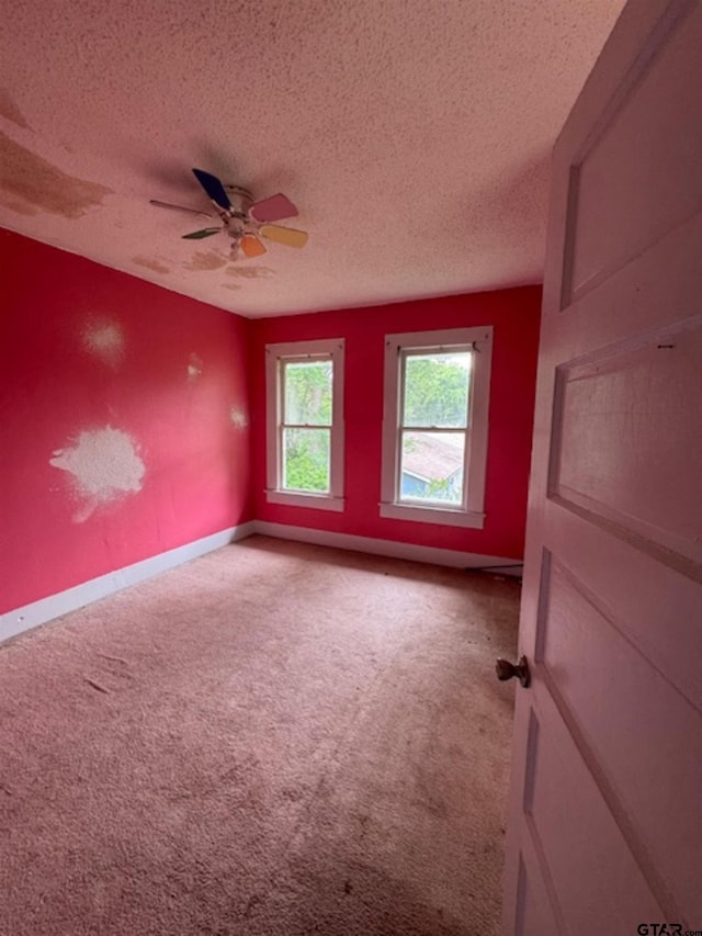 empty room with baseboards, carpet flooring, a textured ceiling, and a ceiling fan