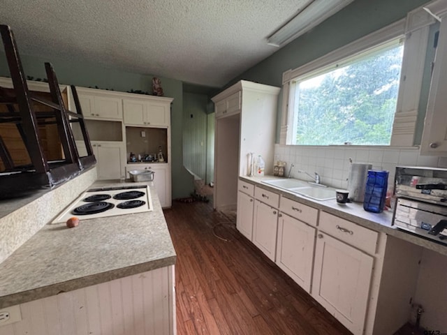 kitchen with a sink, a textured ceiling, white electric cooktop, backsplash, and dark wood-style floors