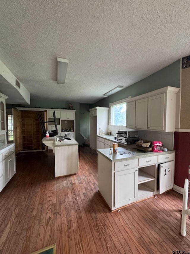 kitchen featuring visible vents, a textured ceiling, a peninsula, and dark wood finished floors