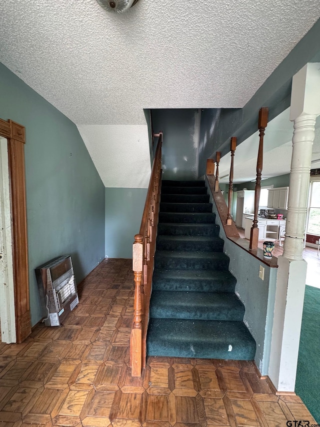 staircase featuring a textured ceiling and vaulted ceiling