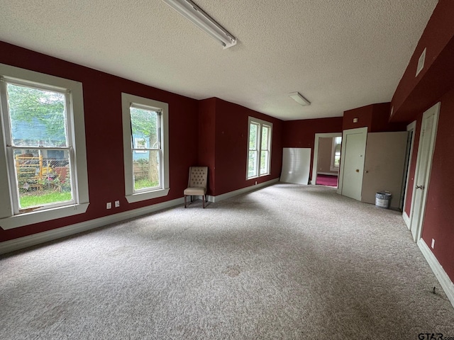 unfurnished living room featuring baseboards, carpet, and a textured ceiling