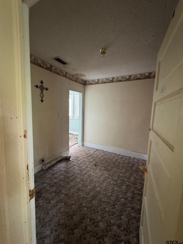 empty room with baseboards, carpet, a textured ceiling, and visible vents