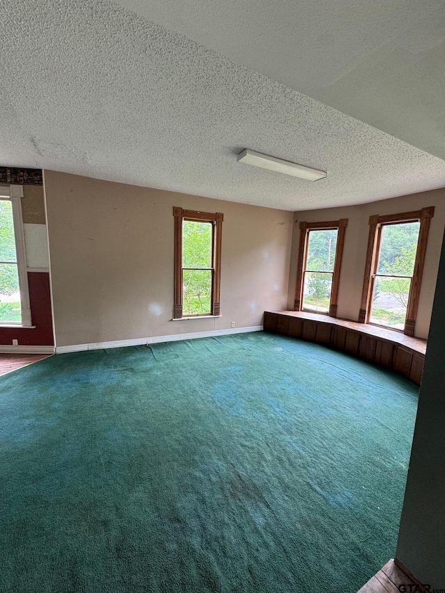 carpeted empty room with a textured ceiling and baseboards