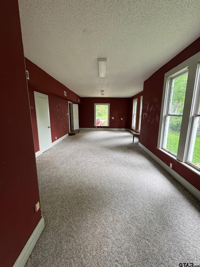 carpeted empty room featuring baseboards and a textured ceiling