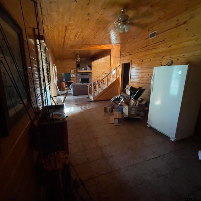 interior space with ceiling fan, wood ceiling, and wood walls