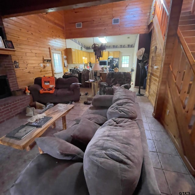 tiled living room with beam ceiling, wood walls, and a towering ceiling