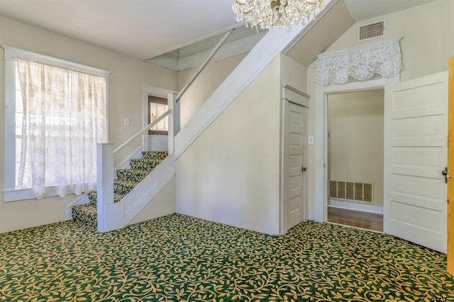 stairs with carpet, plenty of natural light, vaulted ceiling, and a notable chandelier