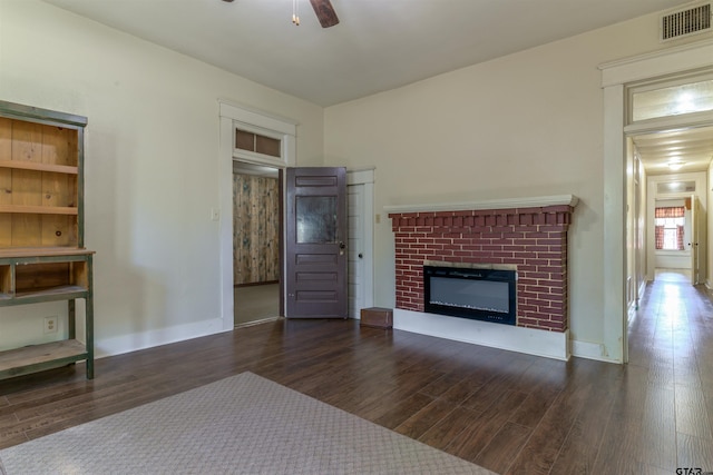 unfurnished living room featuring dark wood-type flooring and a brick fireplace