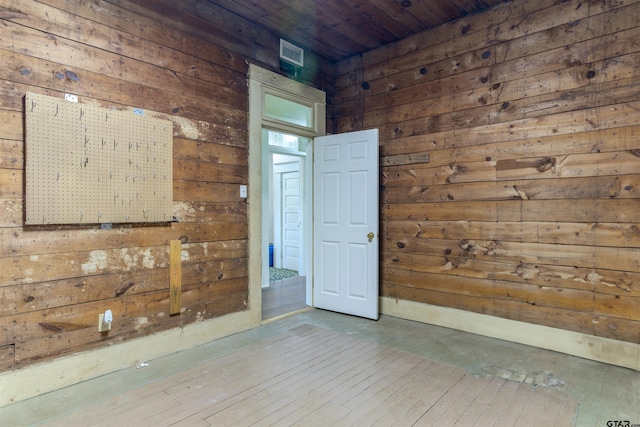 empty room featuring wood walls, wood ceiling, and hardwood / wood-style flooring