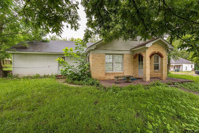 view of front of property featuring a front lawn and a patio