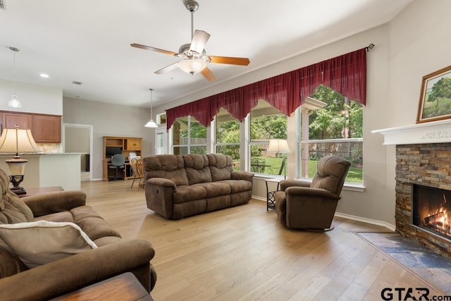 9190 Teal Flight Way, Tyler, TX 75703 - living room with light wood-type flooring, a ceiling fan, a stone fireplace, baseboards, and recessed lighting