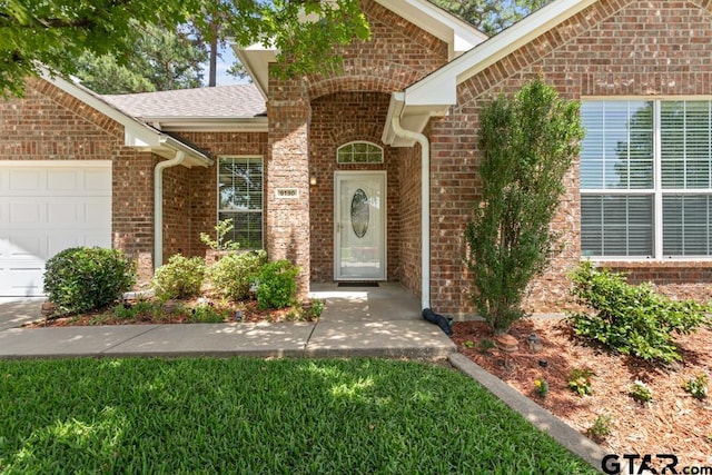 9190 Teal Flight Way, Tyler, TX 75703 - doorway to property featuring an attached garage, brick siding, roof with shingles, and a lawn