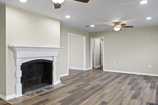 unfurnished living room featuring dark hardwood / wood-style flooring, a tile fireplace, and ceiling fan