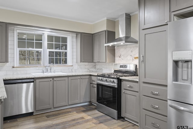 kitchen featuring sink, gray cabinetry, appliances with stainless steel finishes, light stone countertops, and wall chimney range hood