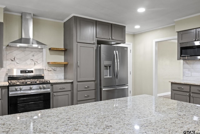 kitchen with crown molding, appliances with stainless steel finishes, light stone counters, and wall chimney exhaust hood