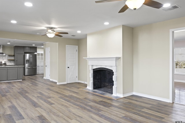 unfurnished living room featuring dark hardwood / wood-style flooring, a fireplace, and ceiling fan