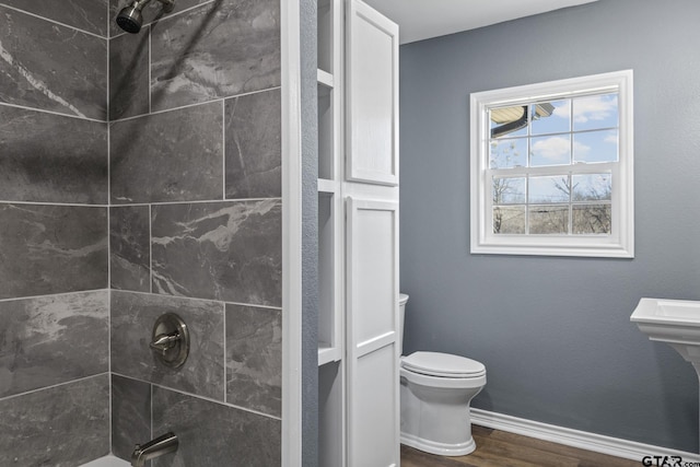 bathroom featuring hardwood / wood-style flooring, tiled shower / bath, and toilet