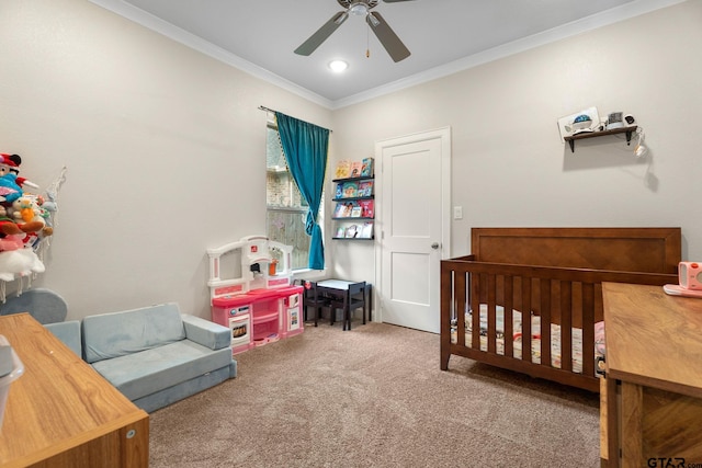 bedroom with ceiling fan, crown molding, a crib, and carpet floors