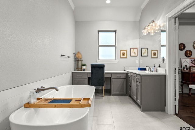 bathroom featuring vanity, a washtub, tile walls, and tile patterned flooring