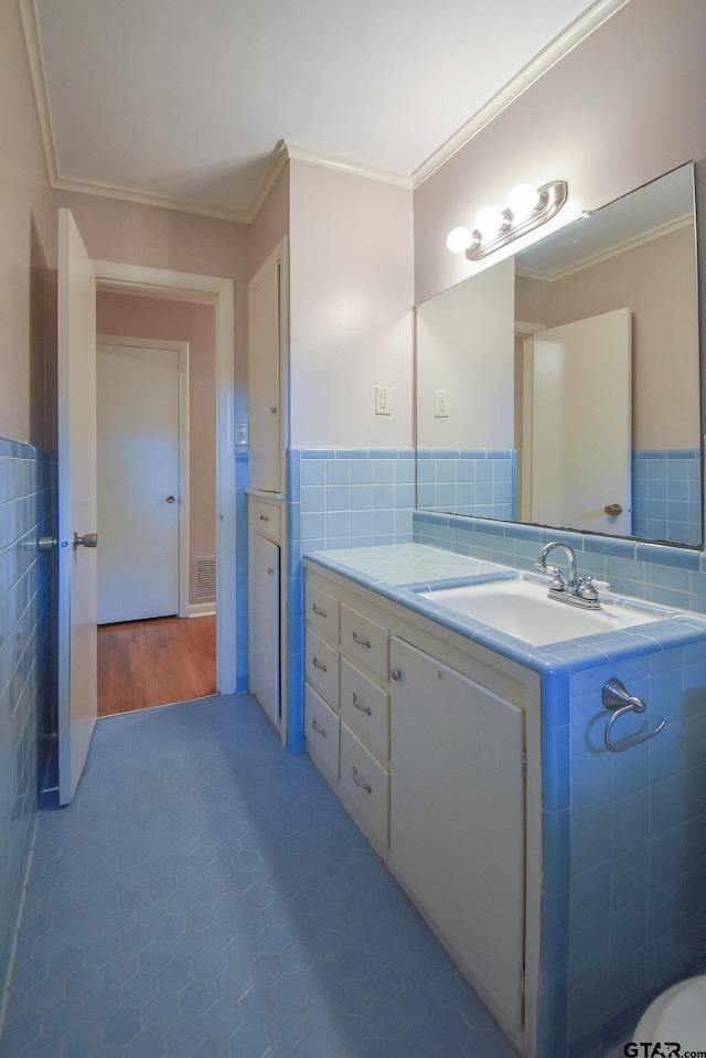 bathroom with tile walls, hardwood / wood-style floors, ornamental molding, and vanity