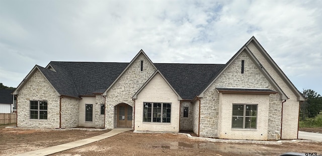 french provincial home featuring brick siding and fence