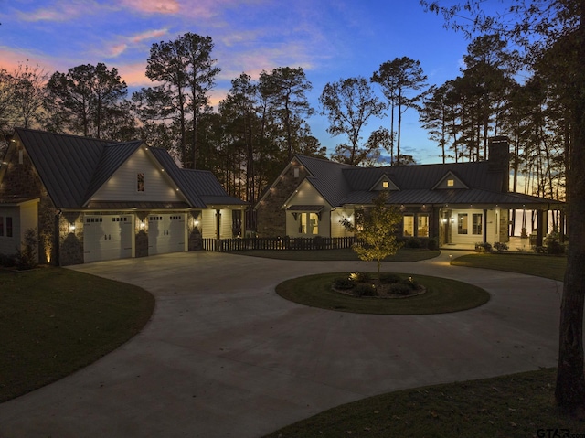 modern inspired farmhouse featuring a standing seam roof, a chimney, curved driveway, and metal roof