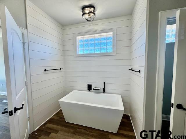 14909 Turtle Creek Ranch Rd, Flint, TX 75762 - bathroom featuring a soaking tub, wood finished floors, and wood walls