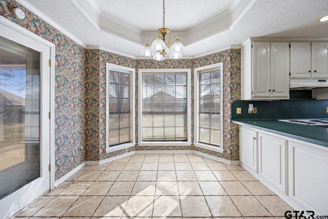 kitchen featuring pendant lighting, a raised ceiling, crown molding, white cabinetry, and a chandelier