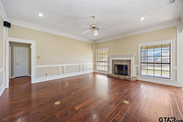 unfurnished living room featuring a textured ceiling, dark hardwood / wood-style floors, a stone fireplace, and ornamental molding