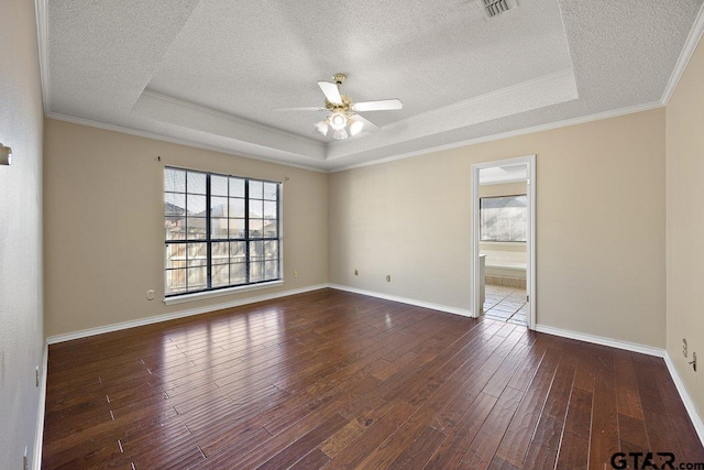 empty room featuring ceiling fan, crown molding, dark wood-type flooring, and a tray ceiling