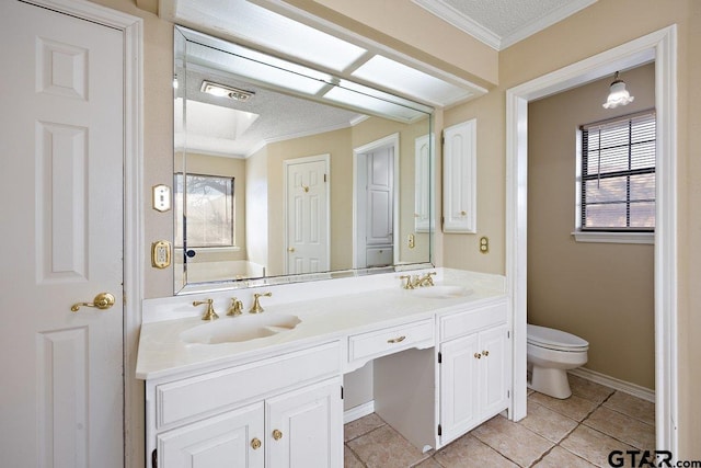 bathroom featuring toilet, vanity, crown molding, and a healthy amount of sunlight