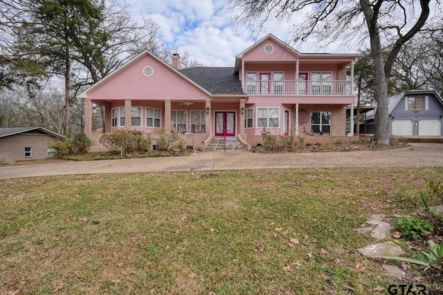 front of property with an outbuilding, a front lawn, a balcony, and a garage