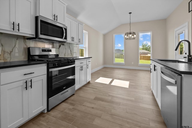 16509 Crossing Cir, Lindale, TX 75771 - kitchen featuring stainless steel appliances, dark countertops, vaulted ceiling, light wood-type flooring, and a chandelier