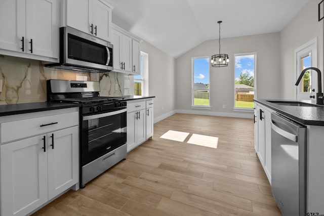 16509 Crossing Cir, Lindale, TX 75771 - kitchen with stainless steel appliances, dark countertops, light wood-style floors, vaulted ceiling, and a chandelier