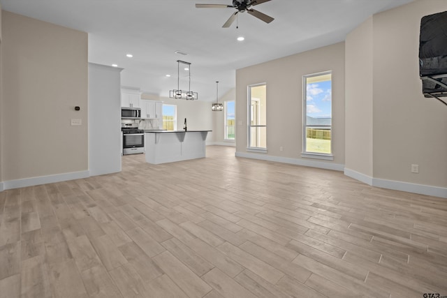16509 Crossing Cir, Lindale, TX 75771 - unfurnished living room featuring ceiling fan, light wood-style floors, a chandelier, and recessed lighting