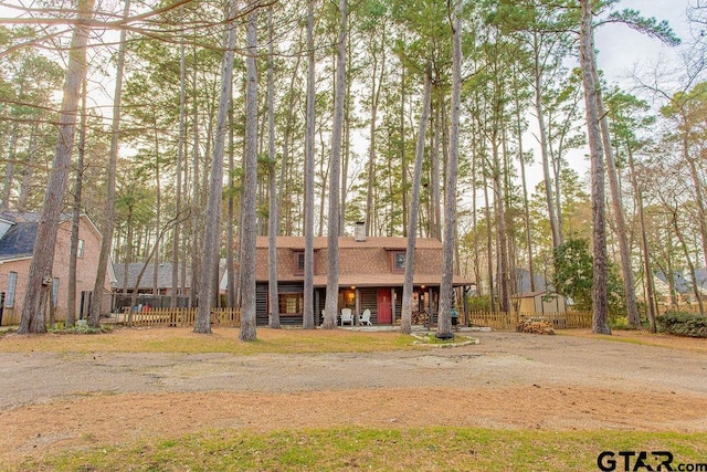 view of front of property featuring a shingled roof, a chimney, and fence